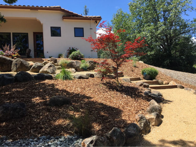 backyard with woodchips and rock landscape